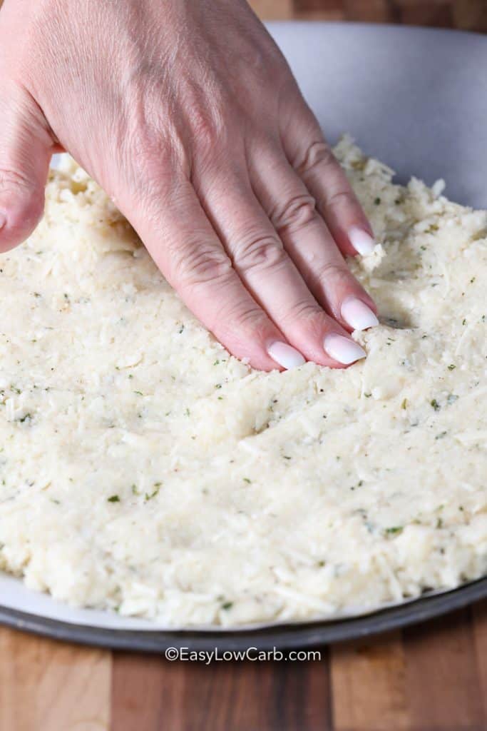 A hand pressing Cauliflower Pizza Crust