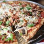 A slice of Cauliflower Pizza Crust being served from the pizza pan