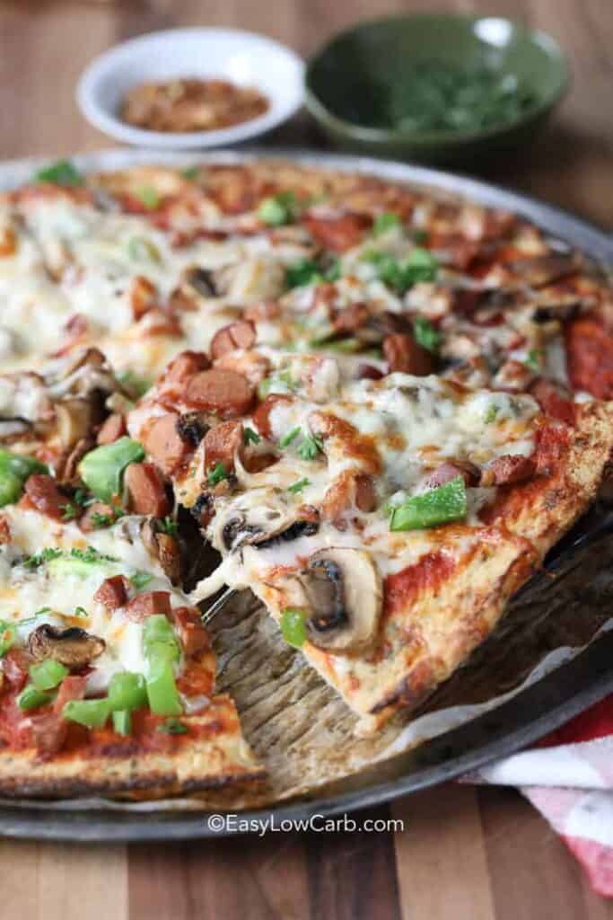 A slice of Cauliflower Pizza Crust being served from the pizza pan