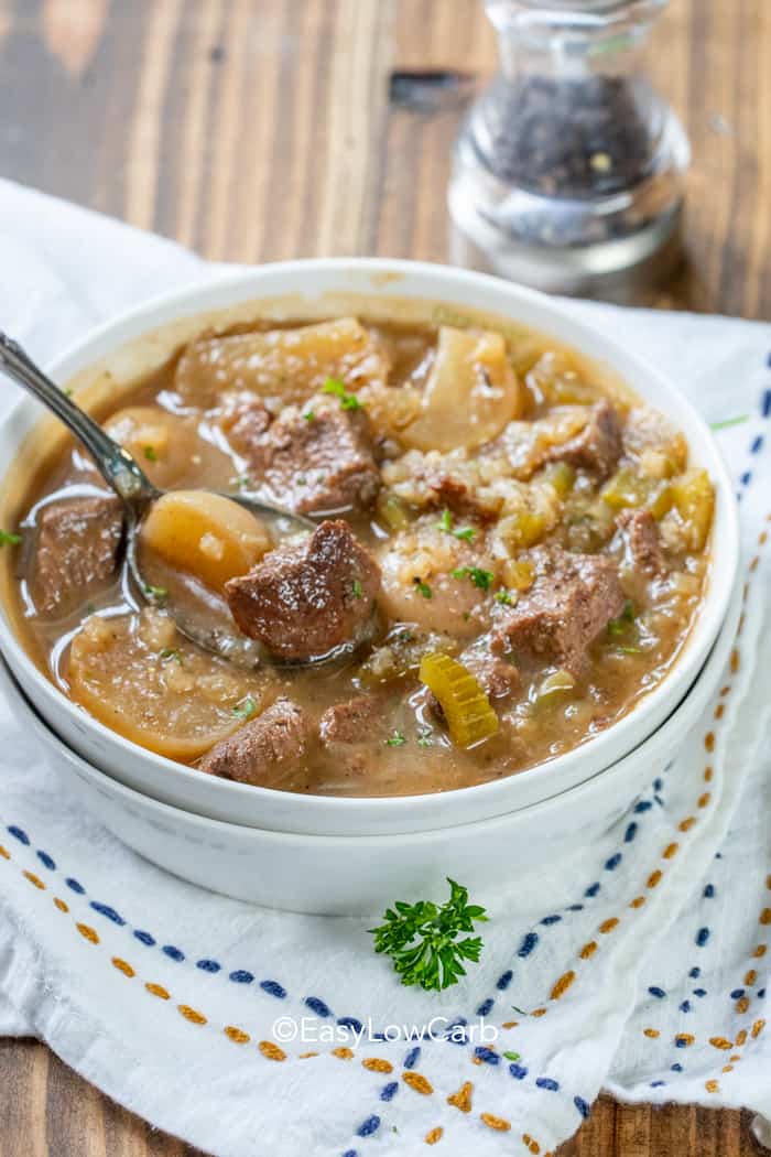 taking a spoonful of Beef Soup with Radishes in a white bowl