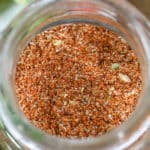 overhead of a glass jar of Taco Seasoning with a spoon on the side