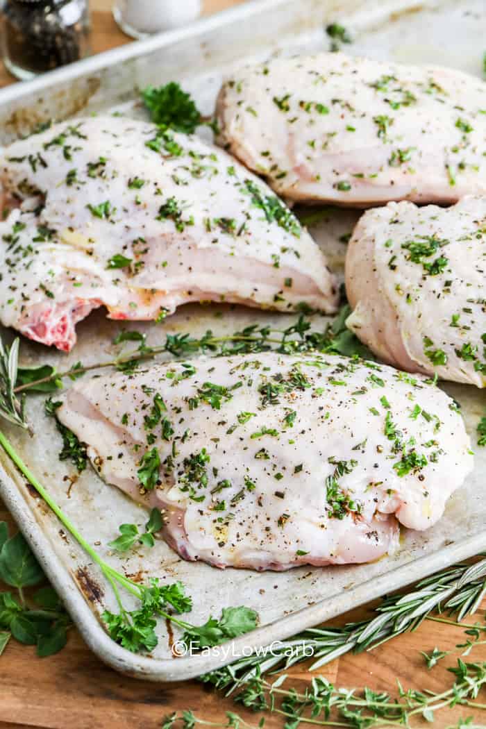 Baked Bone in Chicken Breast coated with herbs on a baking tray before baking