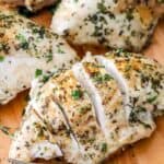 sliced Baked Bone in Chicken Breast with more chicken breasts on the cutting board