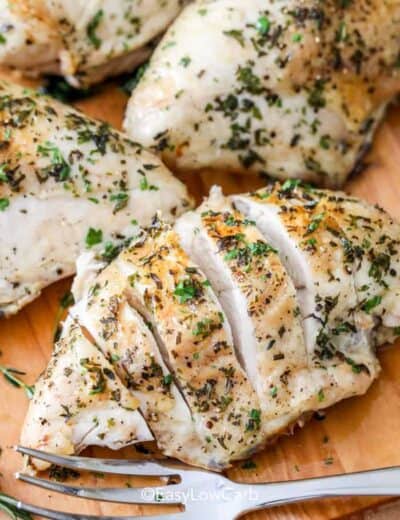 sliced Baked Bone in Chicken Breast with more chicken breasts on the cutting board