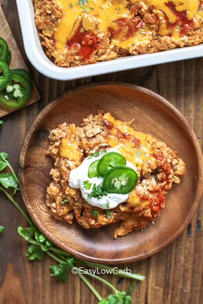 overhead of Cauliflower Enchilada Chicken Casserole on a wood plate with garnish