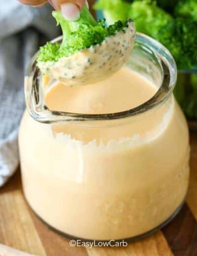dipping broccoli in Keto Cheese Sauce