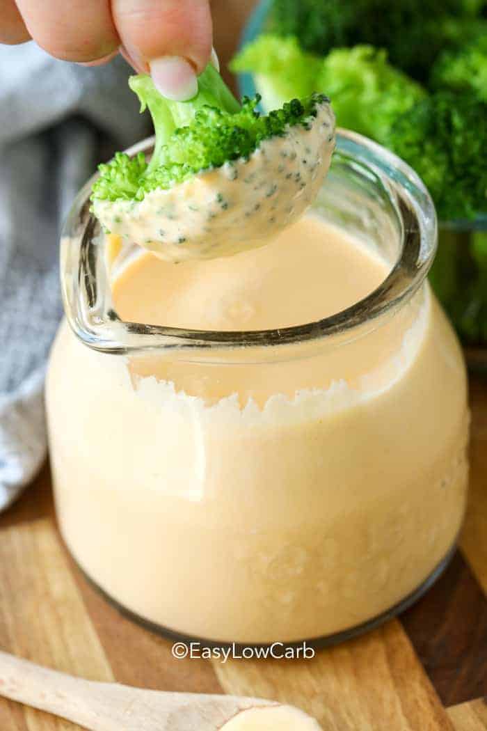 dipping broccoli in Keto Cheese Sauce