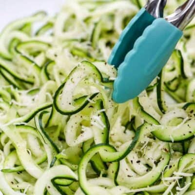 picking up zoodles with blue tongs