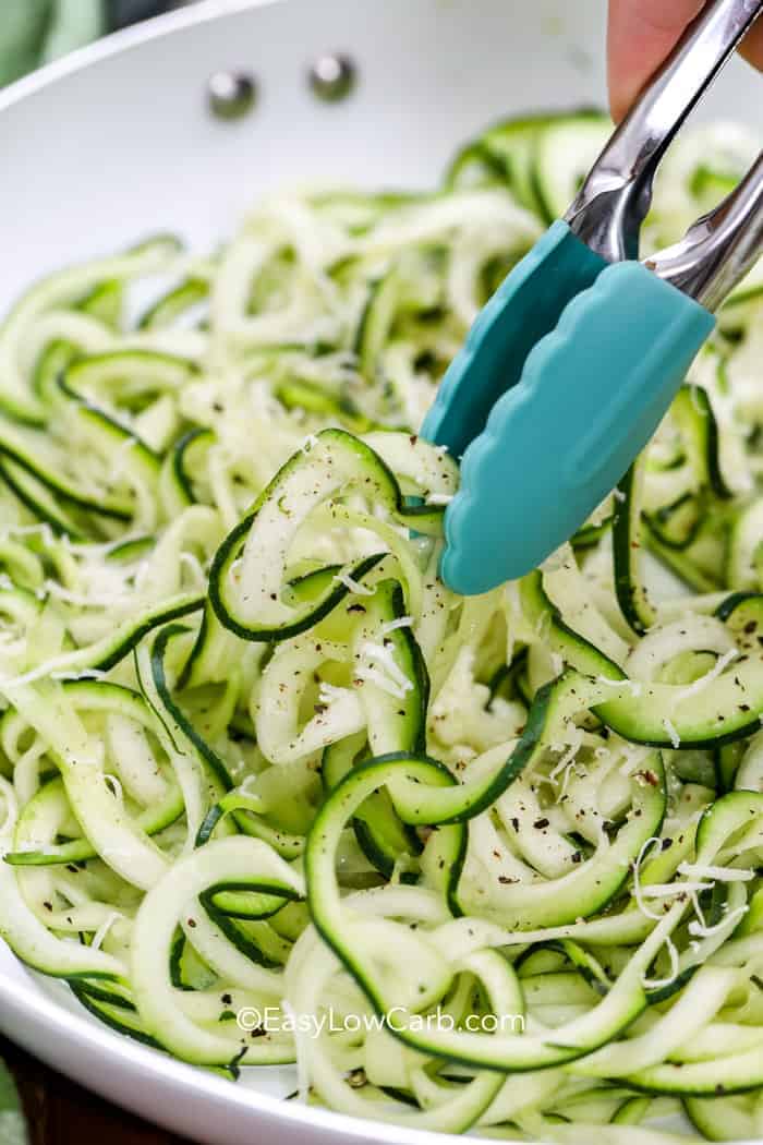 picking up zoodles with blue tongs