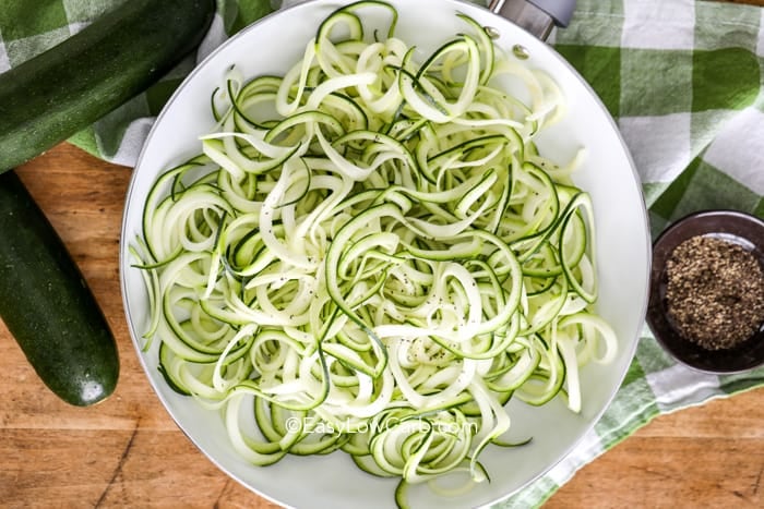 zoodles in a dish with zucchini in the background