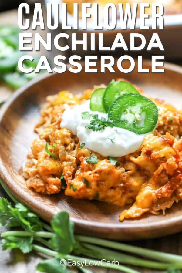 Cauliflower Enchilada Casserole topped with sour cream and jalapenos on a wood plate