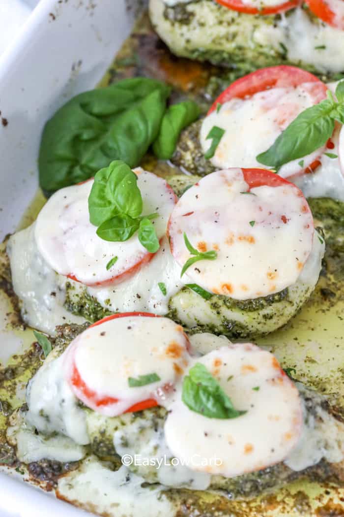 pieces of Pesto Chicken with tomatoes and cheese in the pan