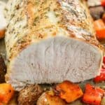 cut Roasted Pork Loin with veggies around on a baking tray