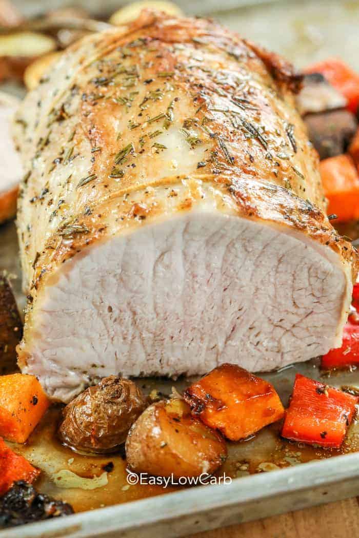 cut Roasted Pork Loin with veggies around on a baking tray