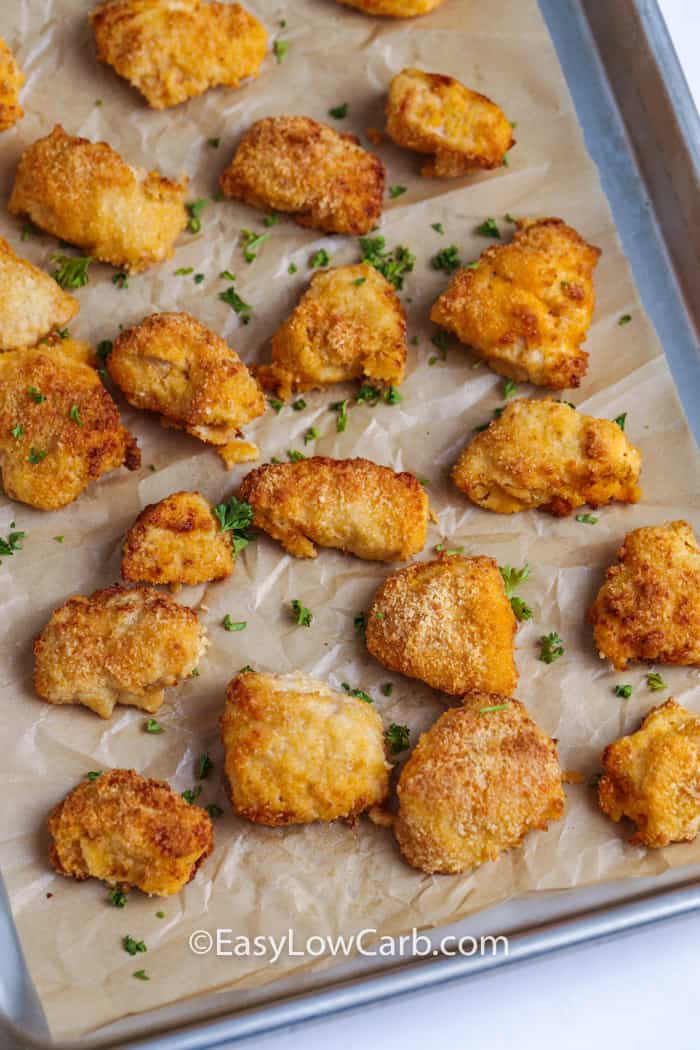 baked buffalo chicken bites with fresh chopped parsley on a parchment lined baking sheet