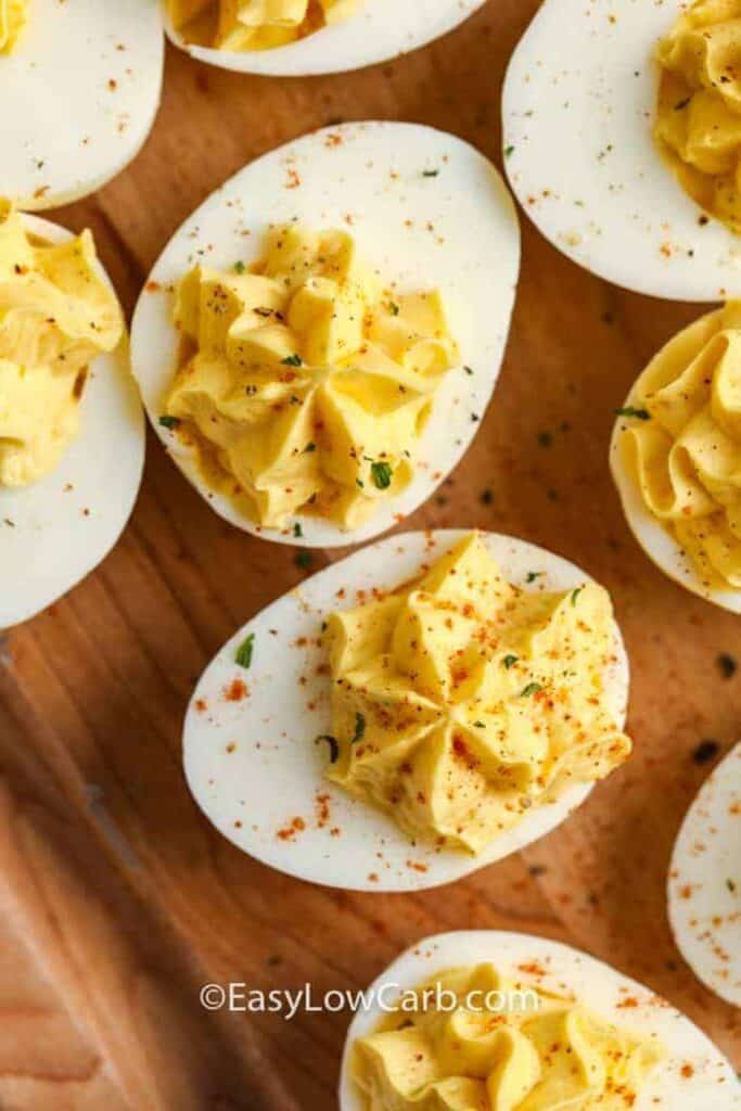 Keto Deviled Eggs on a wooden board garnished with paprika and fresh parsley