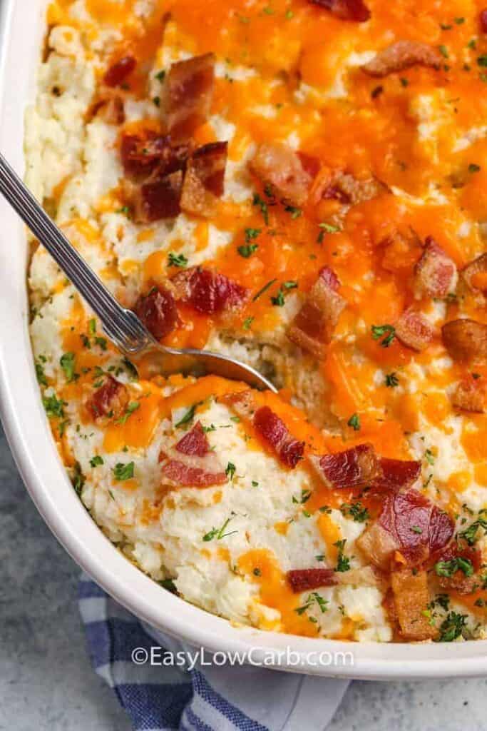 Cauliflower casserole being scooped out with a silver spoon