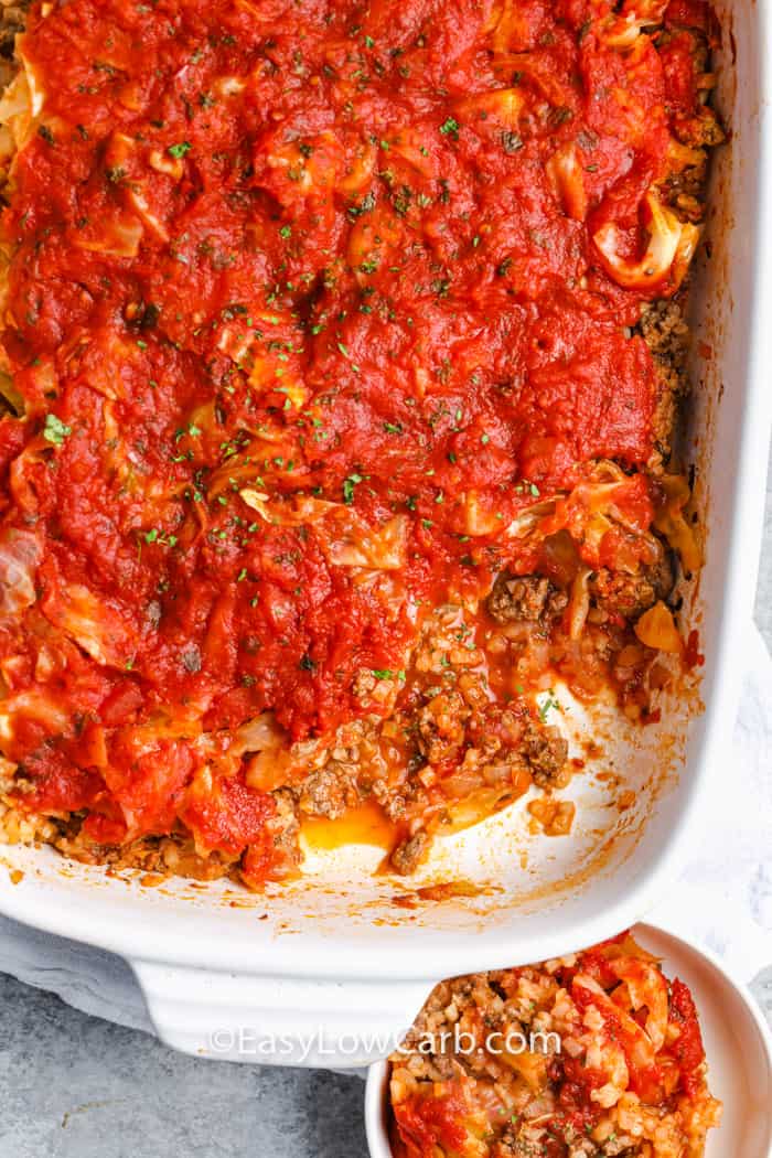 A white baking dish with a serving of unstuffed cabbage casserole removed and in a dish on the side