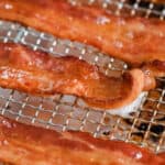 Oven fried bacon slices laid out on a rack with title