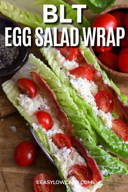 Two BLT Egg Salad Wraps on a wooden board with tomatoes and pepper on the side, with a title.