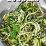 Almond Pesto Zoodles garnished with basil in a white dish with writing