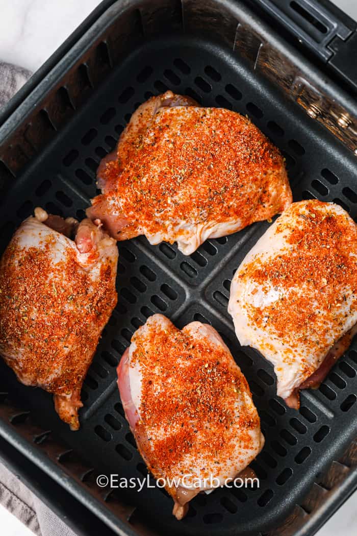 chicken and seasoning in the air fryer to make Air Fryer Chicken Thighs