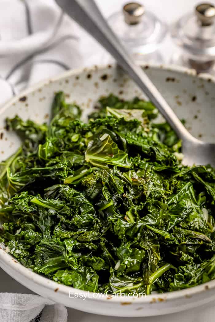 sauteed kale and garlic in a bowl with a spoon.