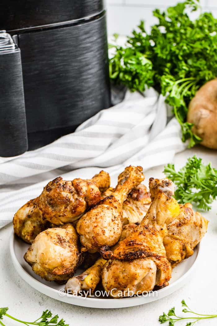 Air Fryer Drumsticks on a plate with air fryer in the back