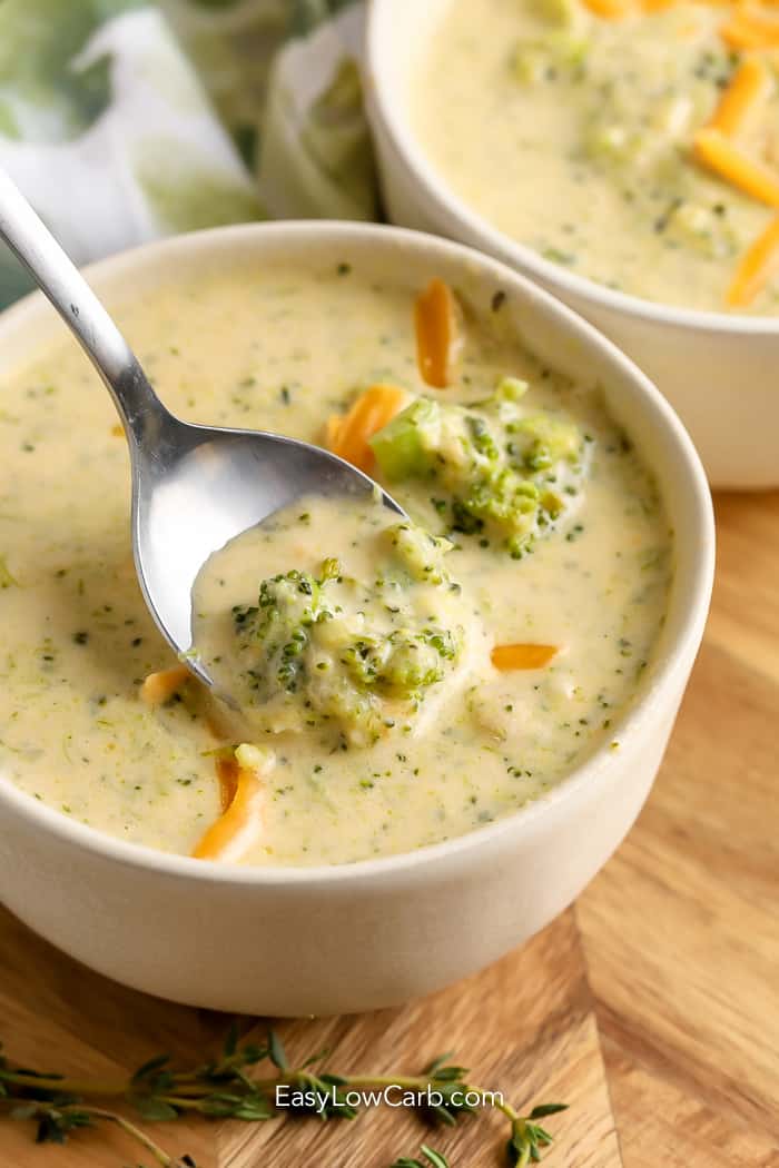 A spoon lifting a serving of Homemade Broccoli Cheddar Soup