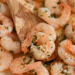 close up of wooden spoon scooping butter garlic shrimp