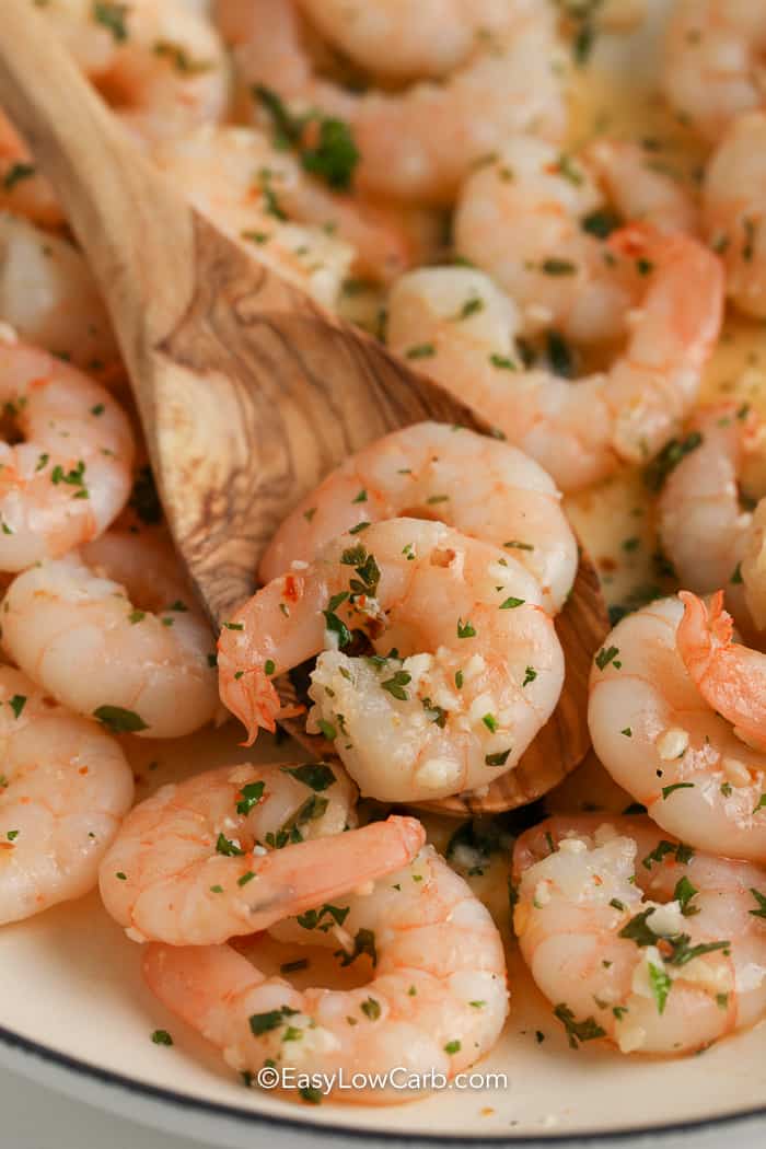 close up of wooden spoon scooping butter garlic shrimp