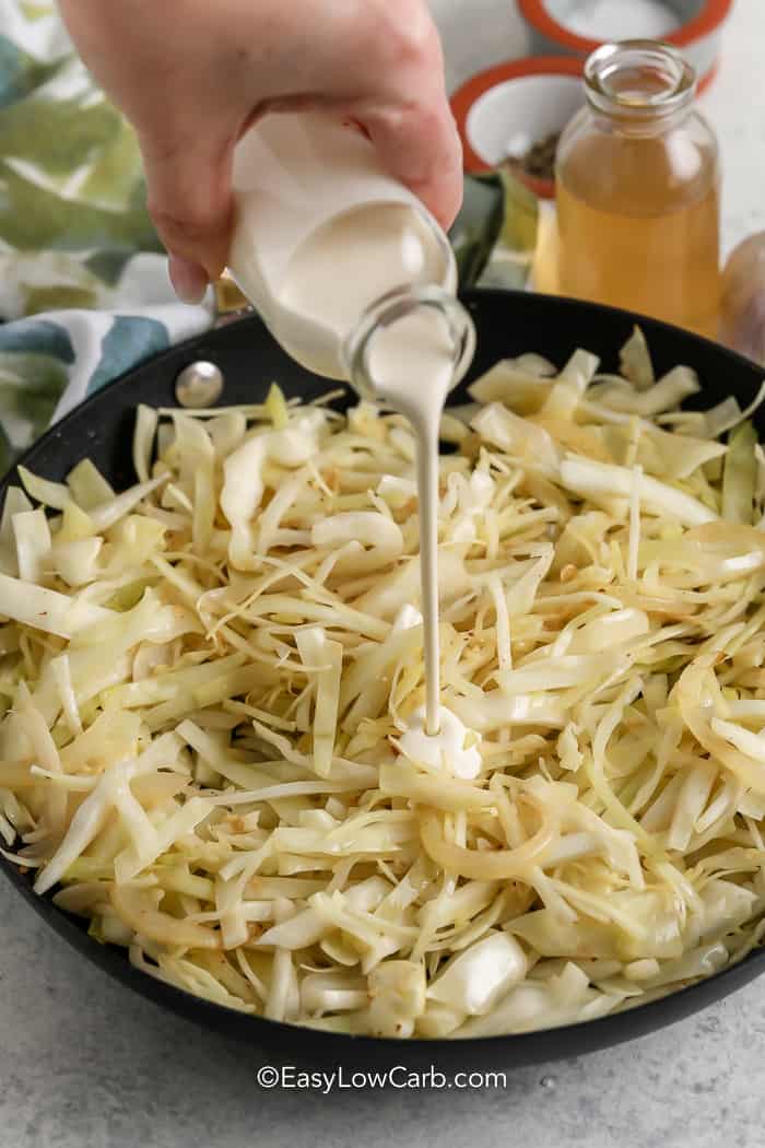 hand pouring cream over cabbage