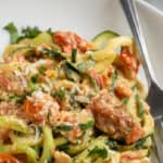 close up of feta zucchini pasta in a white bowl with text