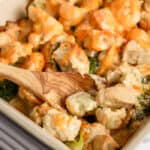 wooden spoon scooping Chicken Broccoli Cauliflower Casserole in a pan