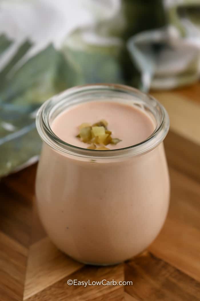 Keto Thousand Island Dressing in a jar with diced pickles on top.