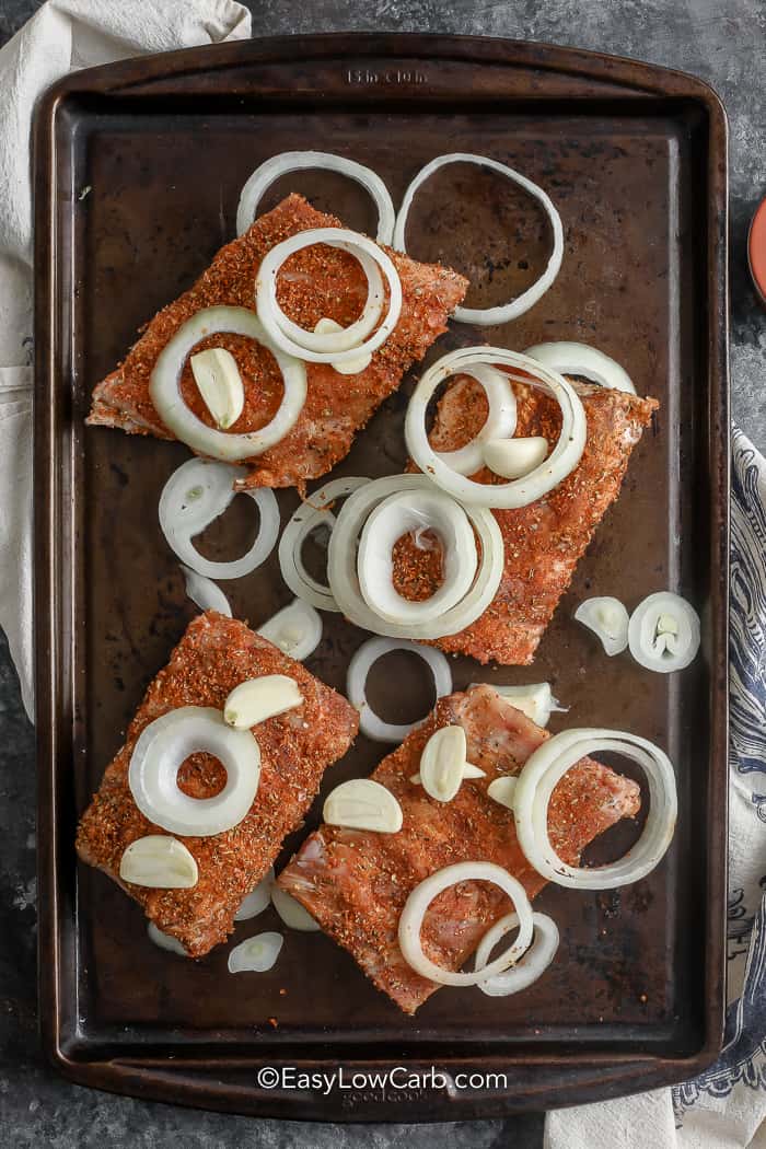 raw Oven Baked Ribs on a sheet pan with onion slices
