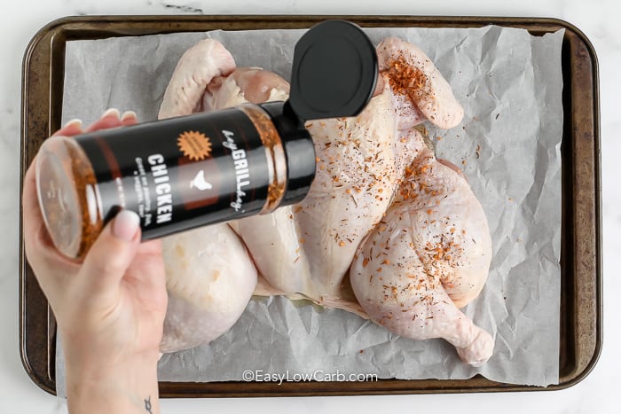 hand sprinkling seasoning Butterflied Chicken