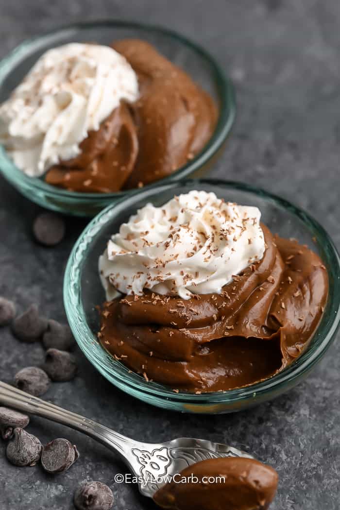 Two bowls of avocado chocolate pudding with whipped cream and chocolate shavings