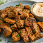 Cajun Pork Bites on a serving plate with dip