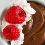 a serving of Avocado Chocolate Mousse with raspberries on top with text.