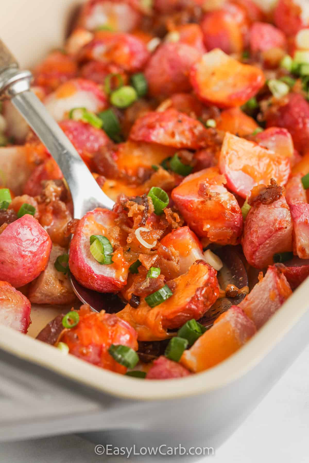 Loaded Baked Radishes Casserole in the dish with a spoon