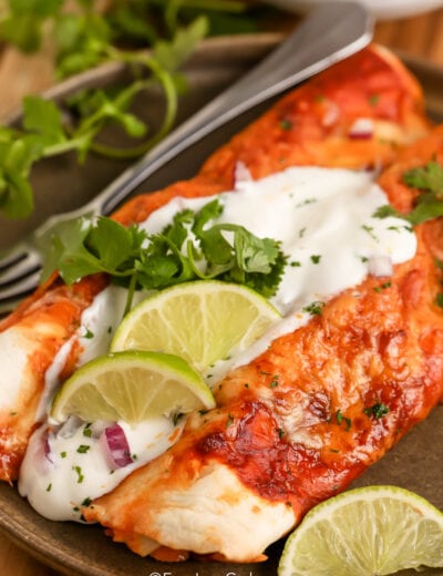 Low Carb Enchiladas topped with sour cream and cilantro with lime wedges