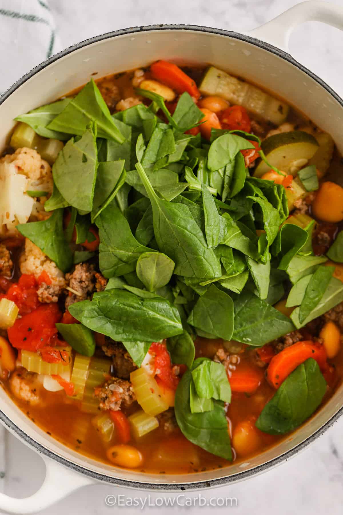 Keto Minestrone Soup in a pot with spinach on top