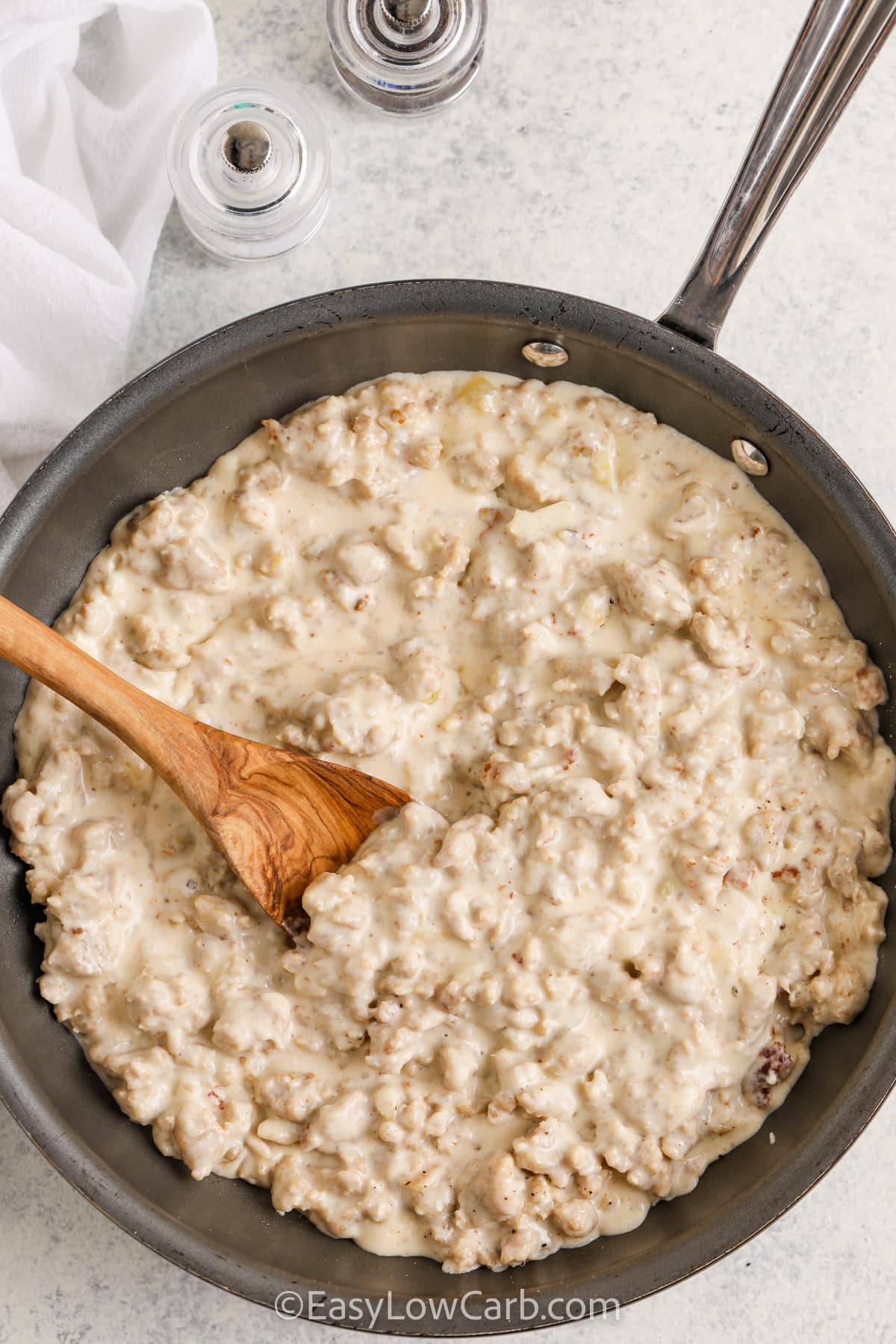 Keto Sausage Gravy in a pan with a wooden spoon