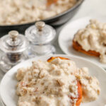 Keto Sausage Gravy with a biscuit on a white plate