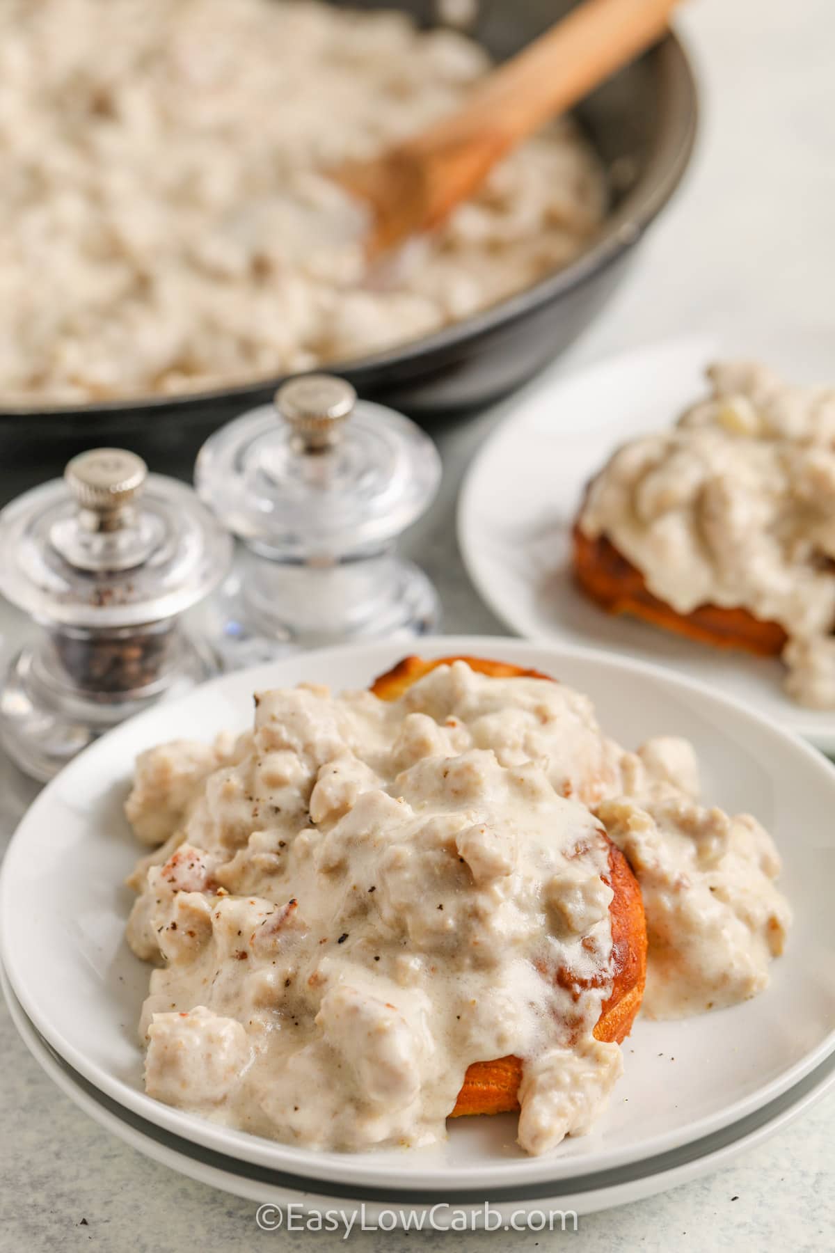 Keto Sausage Gravy with a biscuit on a white plate