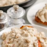 Keto Sausage Gravy on a plate with a biscuit with a title