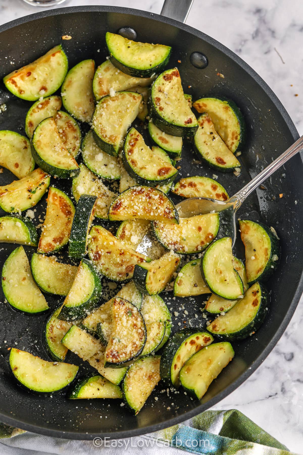 taking a spoonful of Sautéed Zucchini out of the pan
