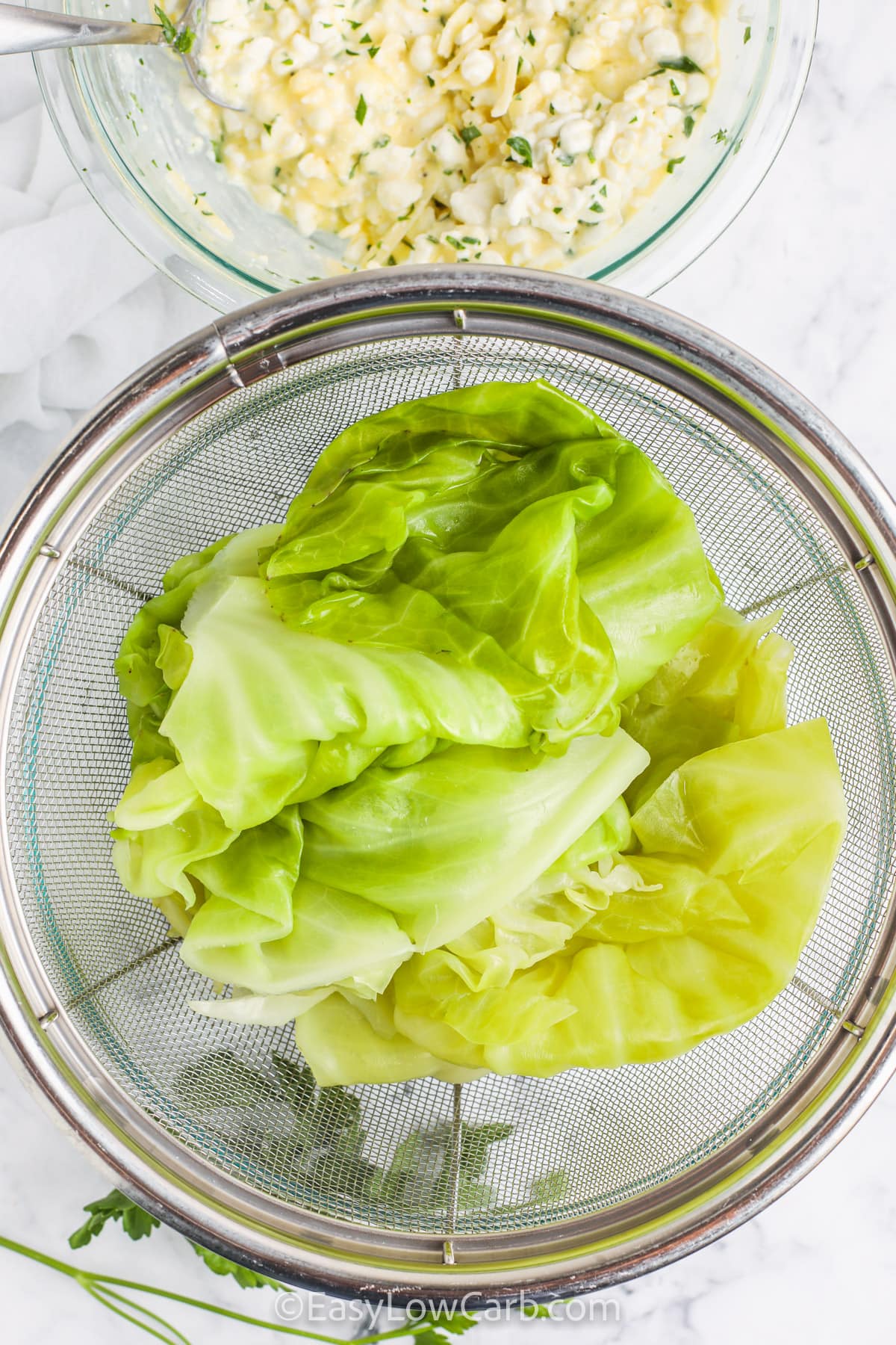 Serve up this easy low carb cabbage lasagna for a cozy dinner everyone will love. Tender cabbage leaves are layered with rich meat sauce and a creamy cheese filling for a hearty meal that tastes like classic lasagna without the carbs. It bakes up thick, slices neatly, and keeps everyone full and happy. Great for weeknights, leftovers, and make ahead meals since it freezes so well for later. #easylowcarb draining cabbage with cheese mixture in a bowl to make Cabbage Lasagna