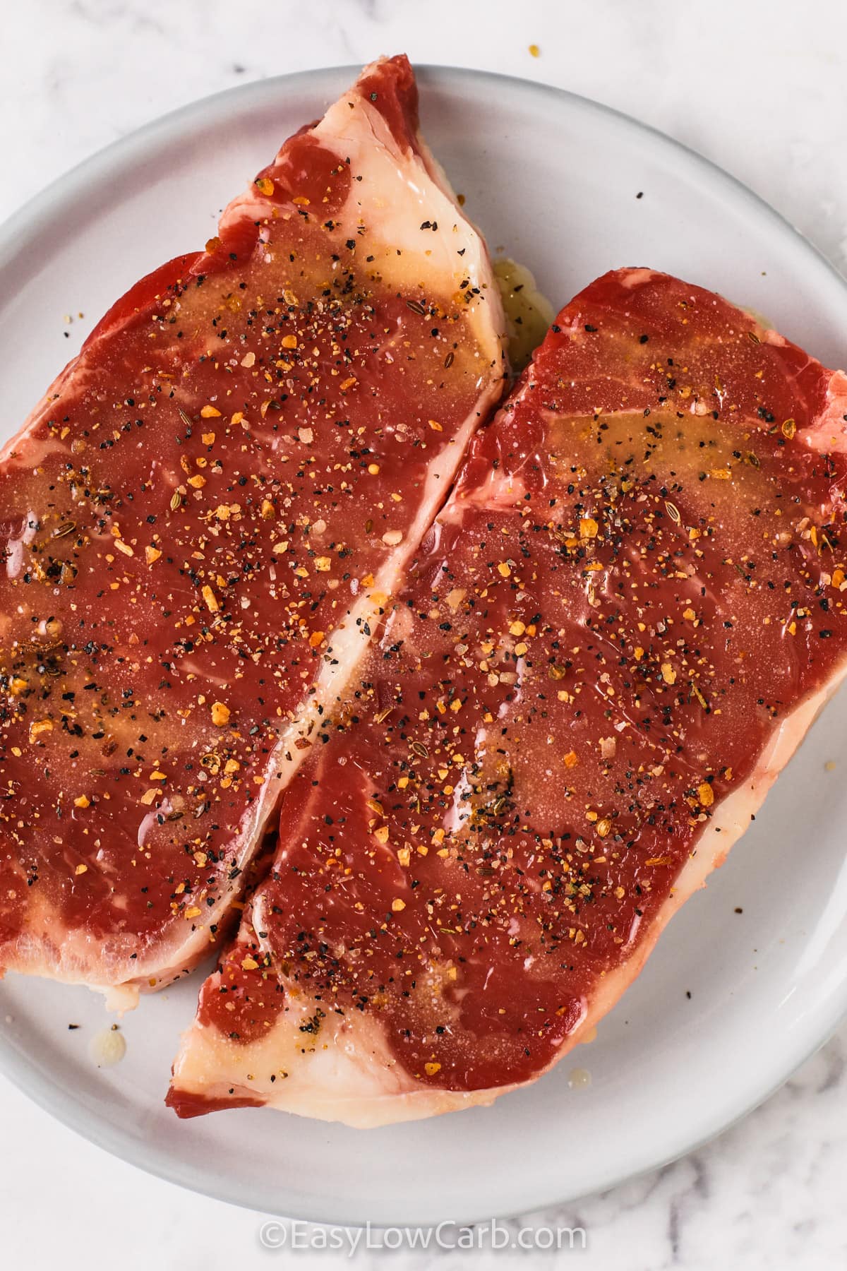 steak with seasoning on a white plate to make Grilled Striploin